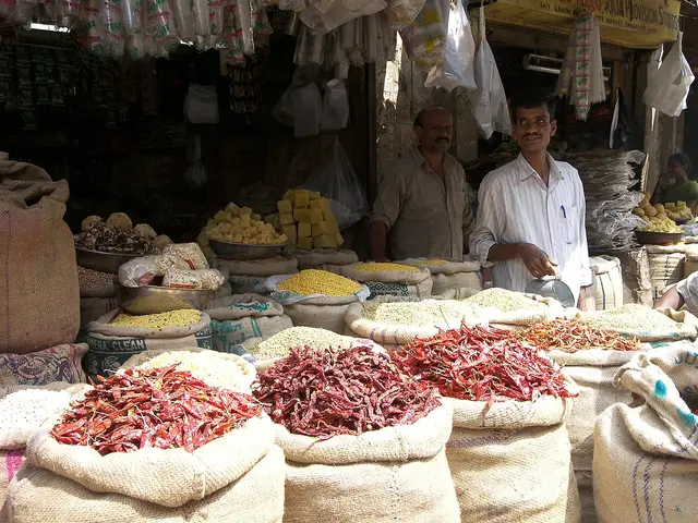 Interior of a small grocery store in a city market in Bangalore, India, with packaged goods on shelves.