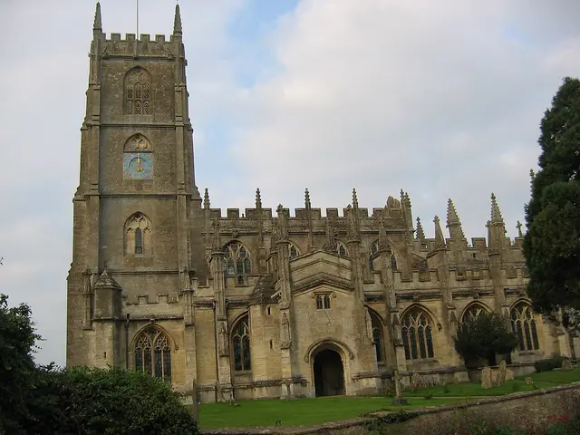 The exterior of a stone English village church with a tall central tower.