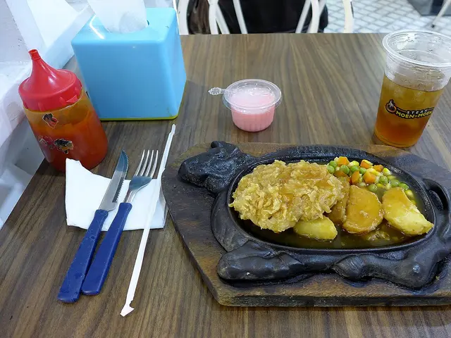 A tenderloin steak on a hot plate served with a dessert at a restaurant.