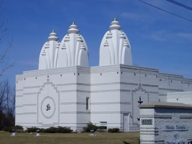 White exterior of the Hindu Temple of Ottawa-Carleton, showing three domed shikhara towers against a blue sky.