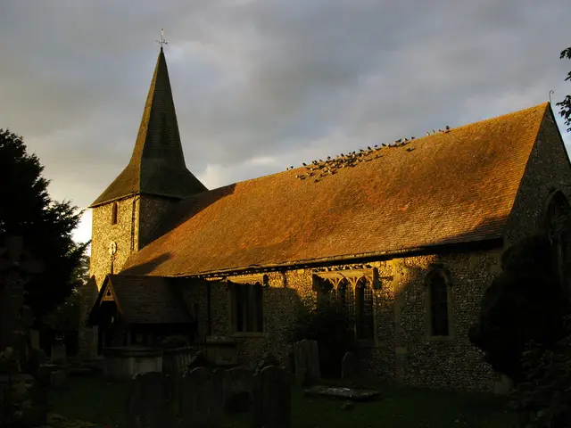 The exterior of a stone parish church at dusk in autumn.