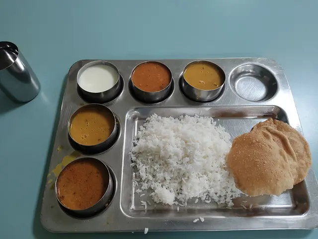 An Indian thali served with poori bread and rice among several side dishes.