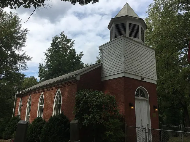 The exterior of a small brick church building with a steeple.