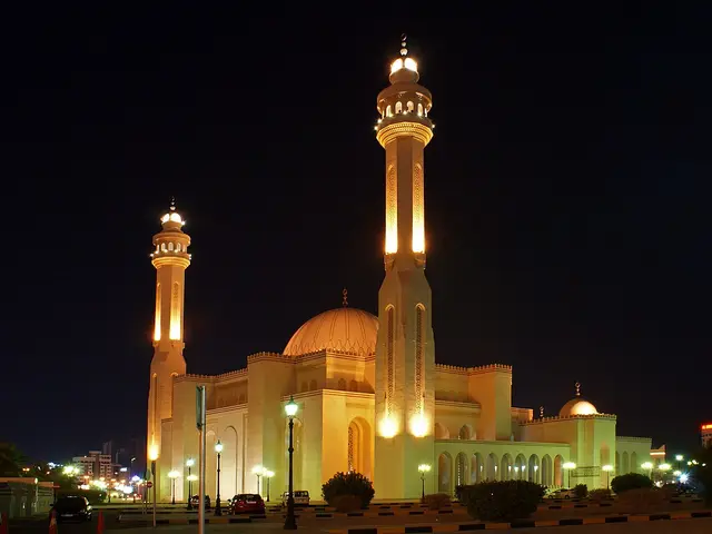 A mosque illuminated at night with tall minarets