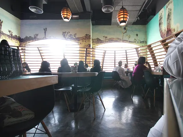Diners seated at tables and a booth inside a restaurant with desert-themed wall murals.