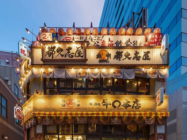 Illuminated facade of a three-storey restaurant with Japanese signage and red paper lanterns in Yurakucho, Tokyo.