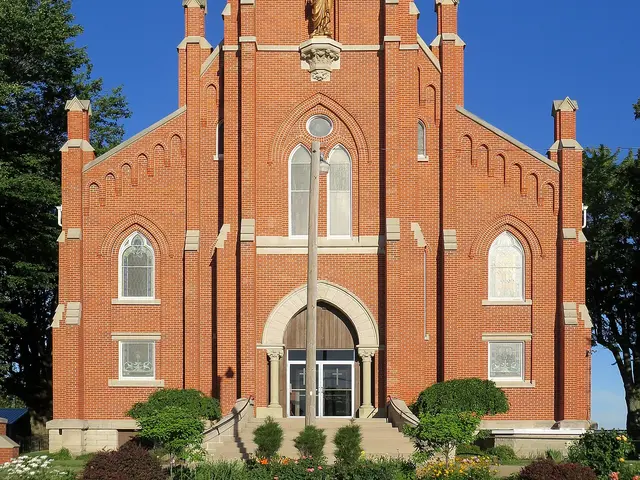 Exterior of Saint Michael's Ridge Catholic Church in Defiance, Ohio, a red-brick church with a tall steeple topped by a gilded statue and cross.