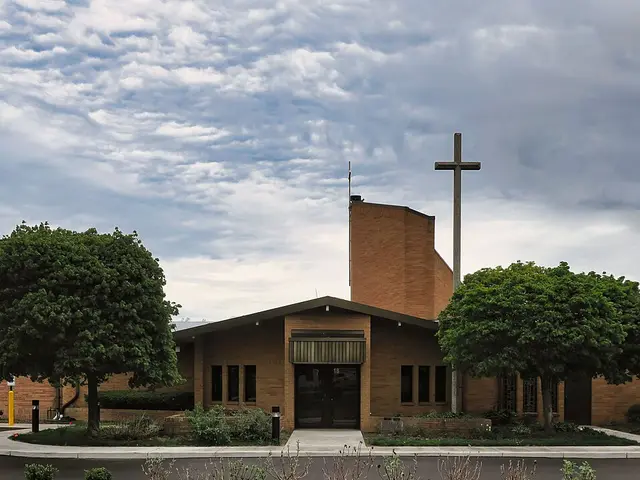 Exterior of Saint Fabian Church, a brick church building with a tall cross in Farmington Hills, Michigan.