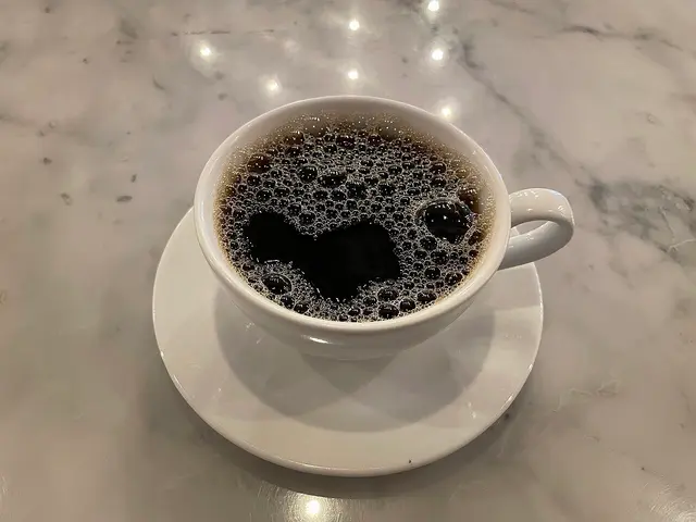 A cup of coffee resting on a cafe table.
