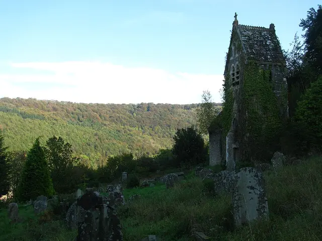 The exterior of a stone church building partly shaded by autumn trees.