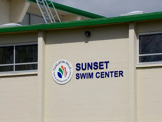Exterior wall signage reading 'Sunset Swim Center' on a public swimming pool facility building.