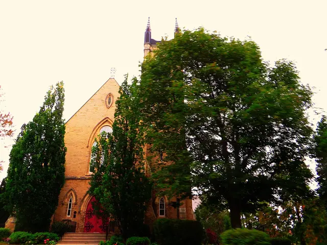 Exterior of St. James Anglican Church in Stratford, Ontario, a buff brick church with a pointed spire, partly framed by trees.