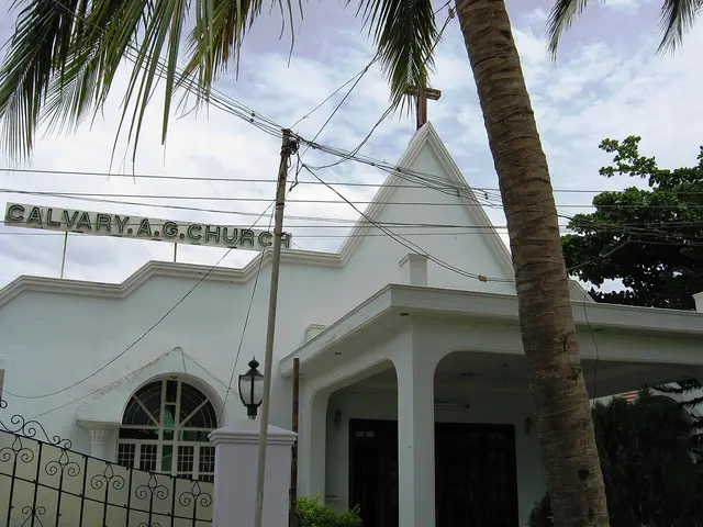 Calvary Assembly of God Church in Salem, India, a white stucco building with a steep gabled roof, a wooden cross, and a palm tree in front.