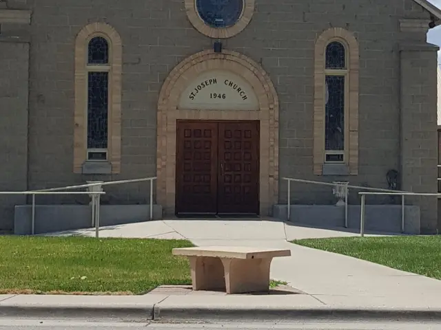 Grey stone Catholic church with a bell tower and rose window, inscribed St. Joseph Church 1946 above the entrance