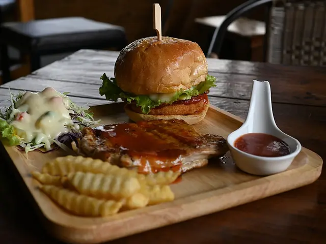 A burger and fries served on a wooden serving board at a restaurant.