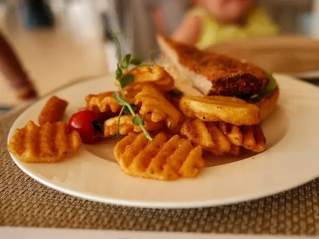 A sandwich with crispy fries and cherry tomatoes served on a plate at a restaurant.