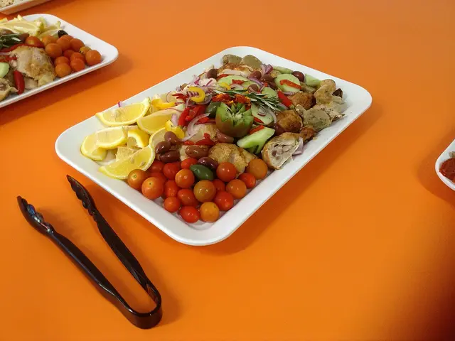 A Mediterranean lunch platter with vegetables, chicken, and olives.