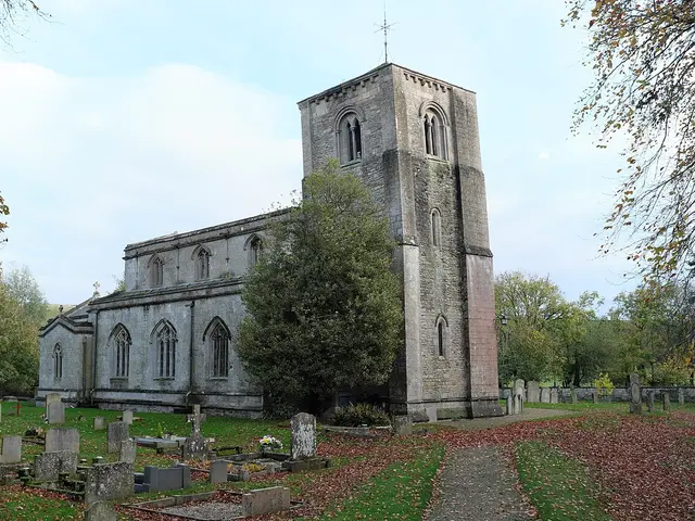 The exterior of a stone church building surrounded by trees in autumn colour.