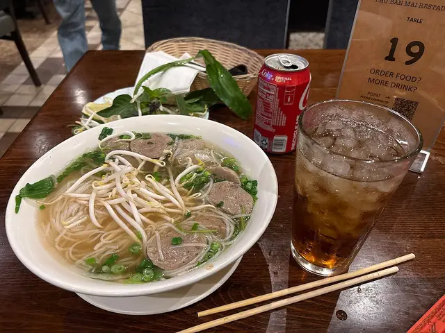 A bowl of Vietnamese meatball pho with a drink.