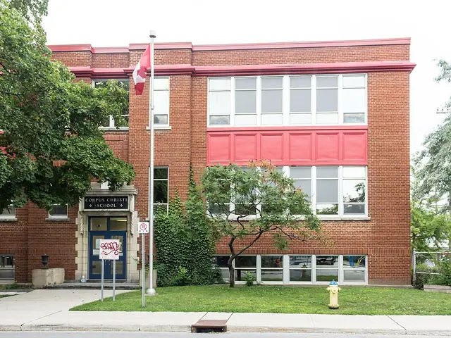 The brick entrance of Corpus Christi School in Ottawa, with the school's name over the door and a Canadian flag