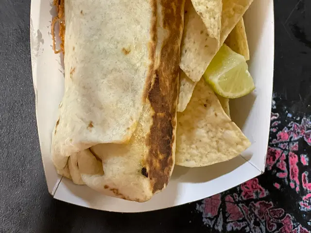 A burrito served with tortilla chips at a taco shop.