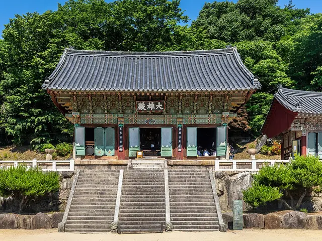 Traditional Korean Buddhist temple hall with tiled roof and painted eaves, approached by stone stairs, at Beomeosa in Busan, South Korea.