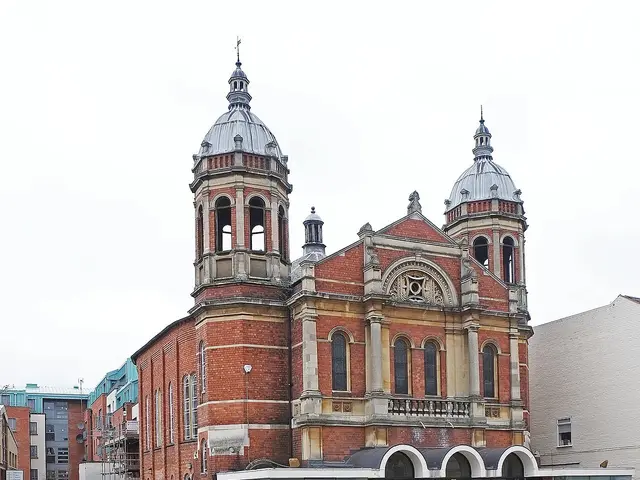 Warwick Road United Reformed Church in Coventry, England, a red brick church with twin domed corner towers and a glass entrance canopy.