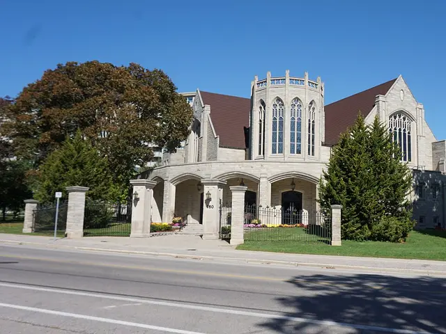 New Apostolic Church on Margaret Avenue in Kitchener, Ontario, a limestone-clad building with a tall Gothic-arched glass turret and twin gables.