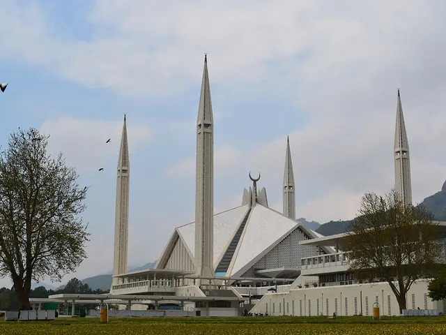 A large modern mosque with sweeping triangular roof and minarets
