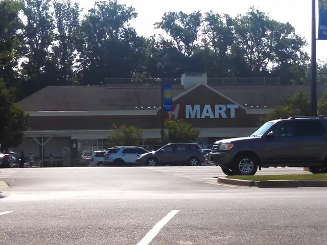 H Mart storefront seen across a parking lot, set among trees with a blue sign above the entrance