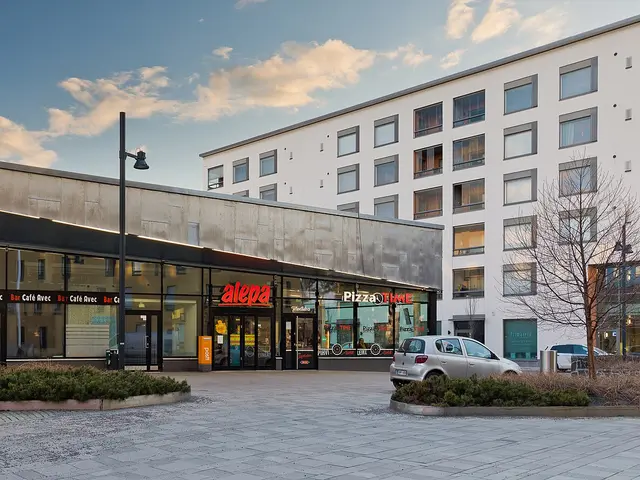 The glass storefront of an Alepa grocery store beneath an apartment building in Vantaa, Finland
