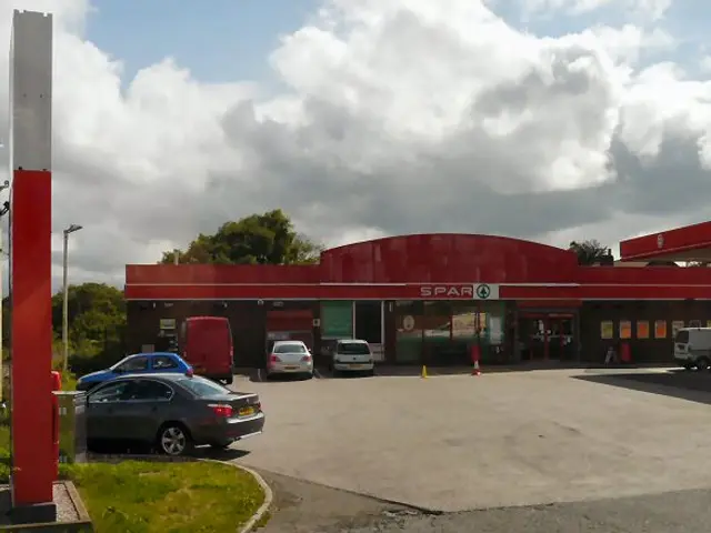 The red-canopied exterior of a Spar grocery store attached to a filling station in England