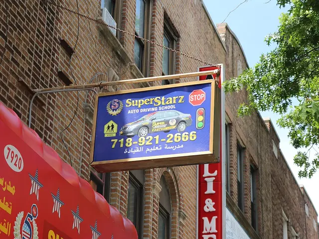 A storefront sign for Super Starz Auto Driving School mounted on a brick building in Brooklyn, New York.