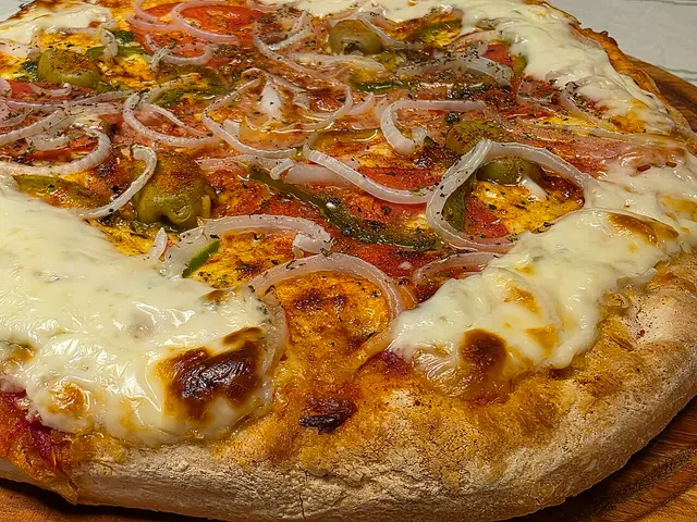 A whole Argentine-style pizza with a thick crust, topped with ham, onion, and olives.