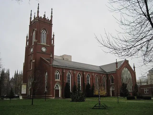 St Paul's Anglican Cathedral in London, Ontario, a red brick Gothic Revival cathedral with a tall clock tower, on an overcast day.