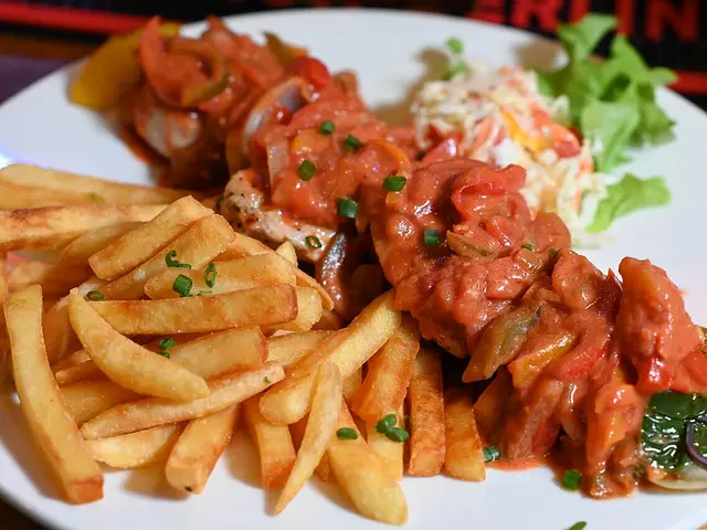 A plate of skewered grilled meat and vegetables with fries and coleslaw at a restaurant.
