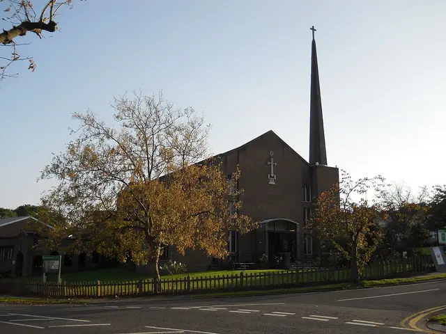 The exterior of a brick church building surrounded by autumn foliage.