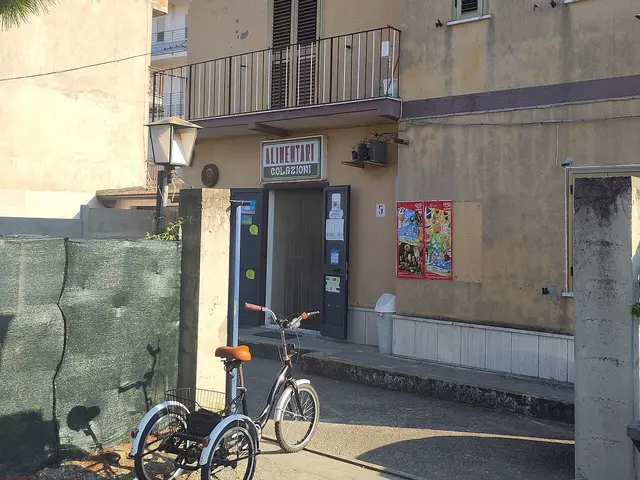 Small Italian 'Alimentari' grocery storefront in a rural village, with a bicycle parked outside.