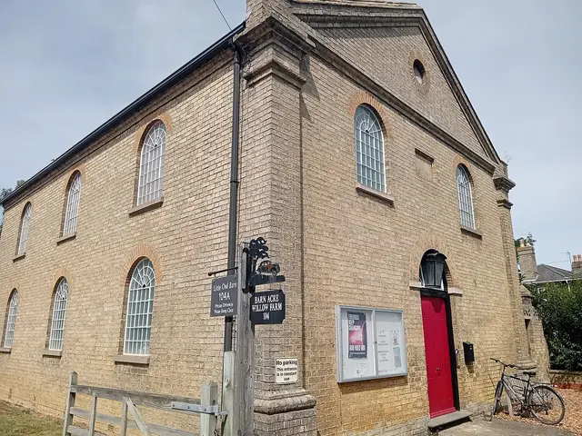 Exterior of the Landbeach and Milton Baptist church building, a yellow brick building with arched windows and a red door.