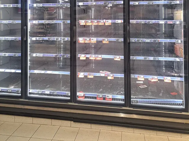A grocery store freezer aisle for ice cream, with the shelves mostly empty.