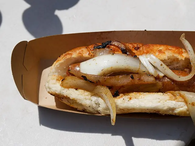 A hot dog topped with onions from a festival food stall.