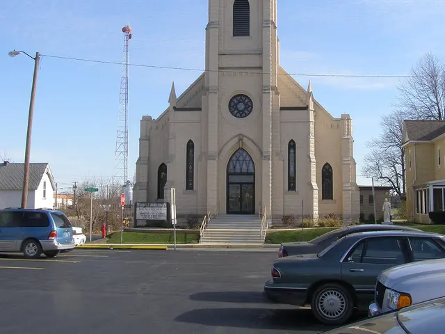 Exterior of St. John's Catholic Church, a stone church building with a steeple in Hartford, Indiana.