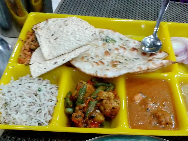 A North Indian thali served at a restaurant with rice, bread, and side dishes.