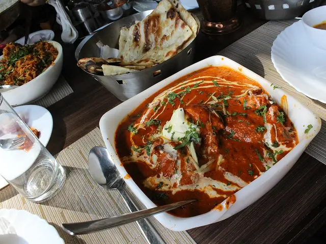 A bowl of creamy butter chicken served with garlic naan bread.