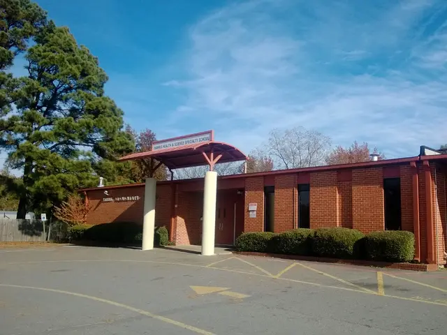 The brick entrance of a general education school, with a covered walkway and the school's name on a sign.