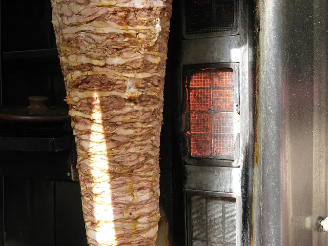 A shawarma stand with meat roasting on a vertical spit.
