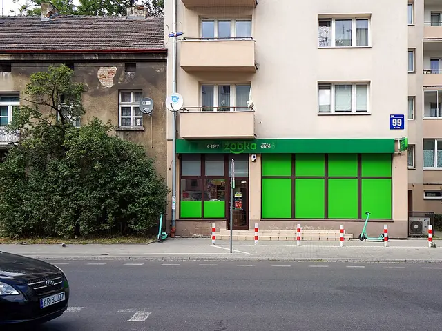 The bright green storefront of a Żabka grocery store on a residential street in Kraków, Poland