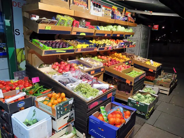 Boxes of fresh fruit and vegetables displayed outside a corner grocery store at night.