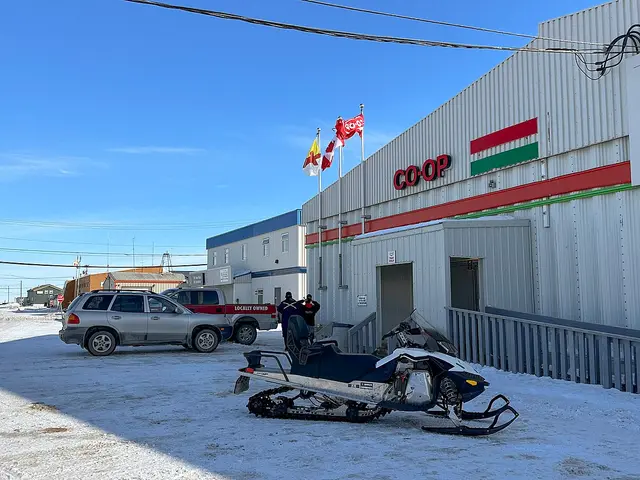 The exterior of a Co-op grocery store in the Arctic community of Cambridge Bay, Nunavut, with a snowmobile parked outside