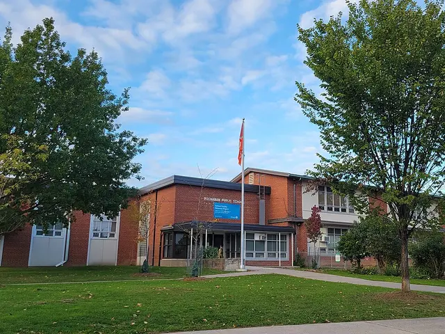 The brick exterior of Buchanan Public School with its name sign and a flagpole out front